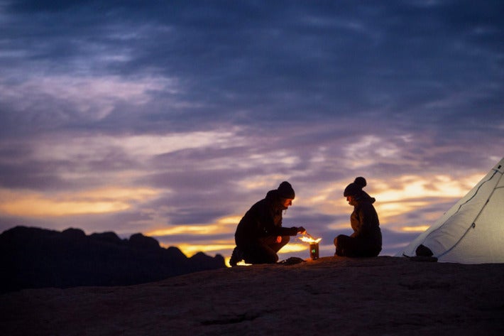 Two campers using a BioLite camp stove outdoors.